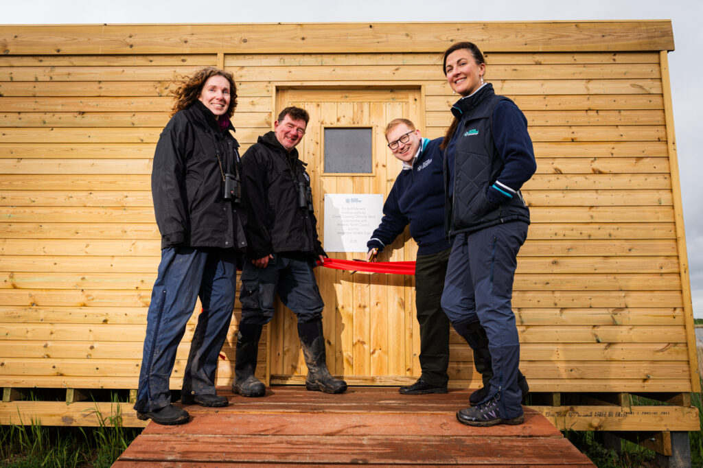 Sarah Craythorne and Dave Miller of Lincolnshire Wildlife Trust with Greg Tomlinson and Jenny Marsden of Outer Dowsing Offshore wind at the new hide. They are cutting a red ribbon to the hide.